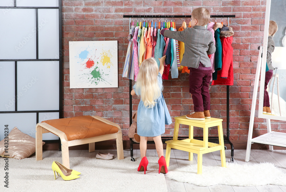 Cute little children choosing clothes in dressing room