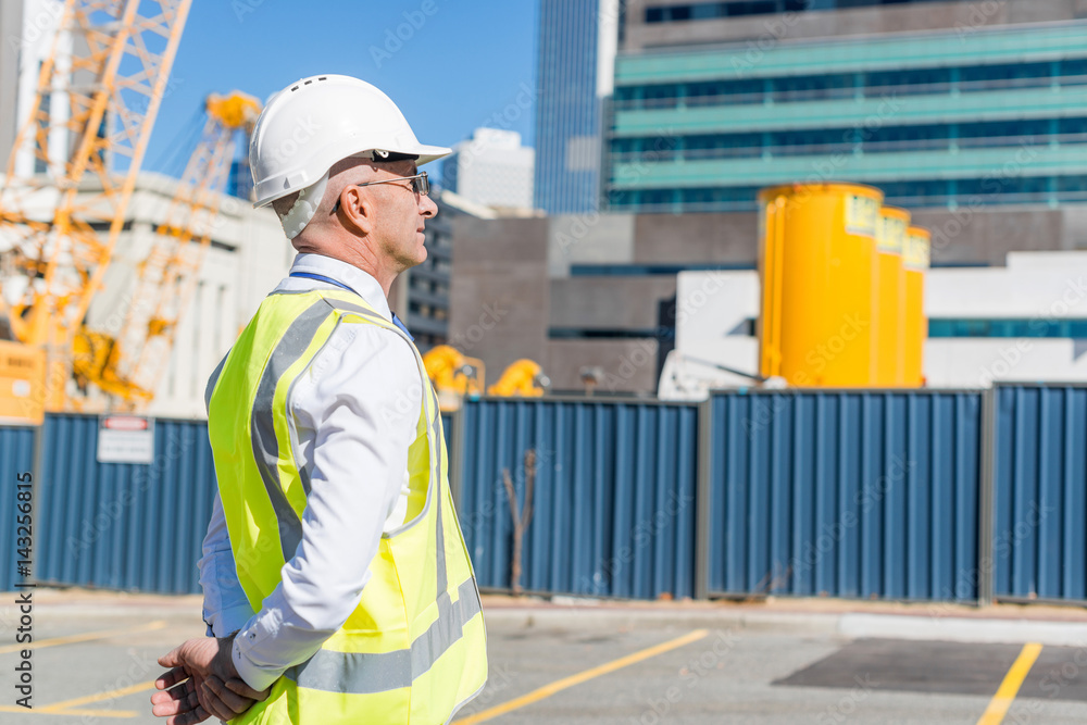 Senior foreman in glasses doing his job at building area on sunny day