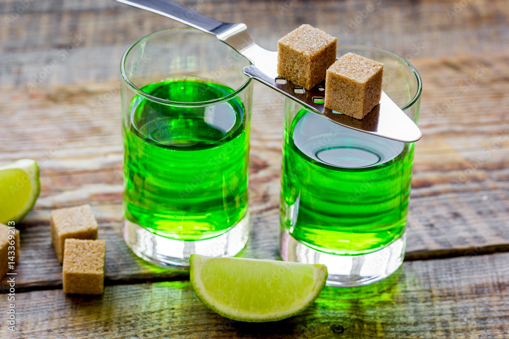 absinthe shots with lime slices and sugar on wooden table background