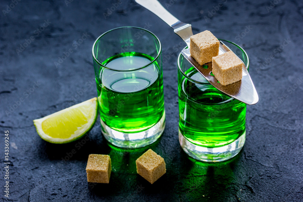 absinthe with sugar cubes in spoon on dark background