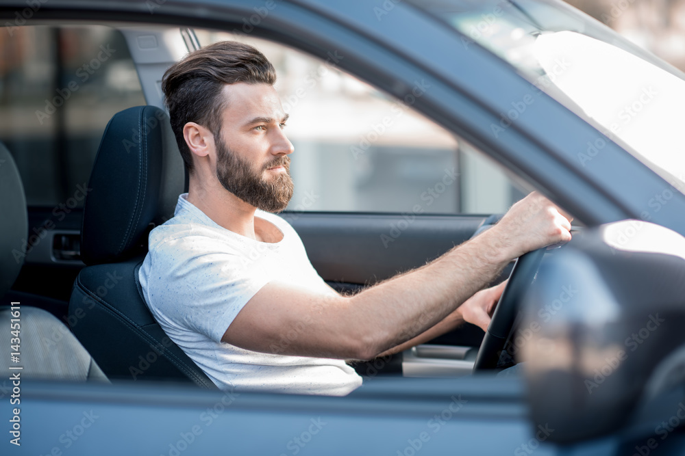 Handsome man dressed casual in white t-shirt driving a car in the city