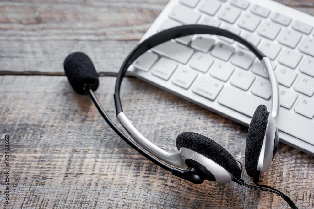 Office desk with headset and keyboard wooden background