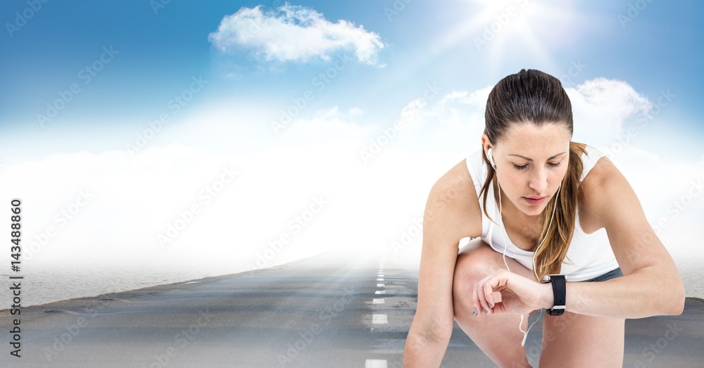 Female runner with headphones on road against sky and sun