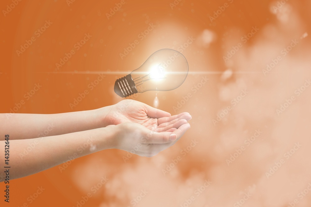 Digital composite image of light bulb over hands