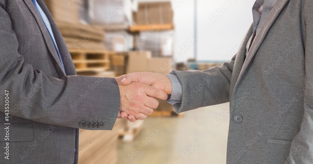 Midsection of businessmen doing handshake in warehouse