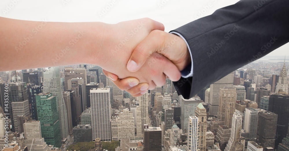 Cropped image of businessmen doing handshake against city