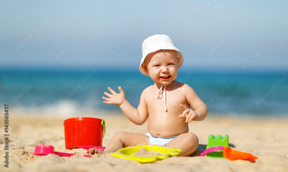 baby boy playing with toys and sand on beach