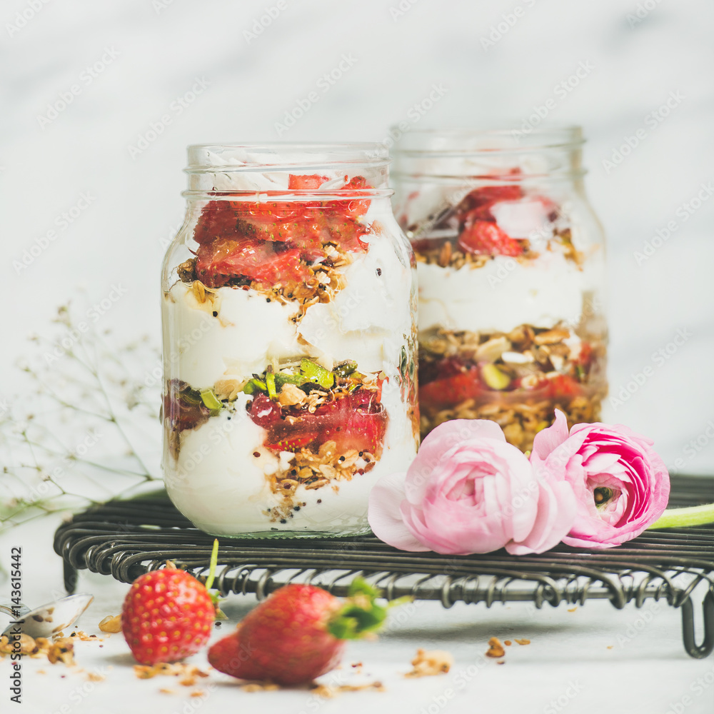 Healthy spring breakfast. Greek yogurt, granola, fresh strawberry breakfast in jars, pink raninkulus