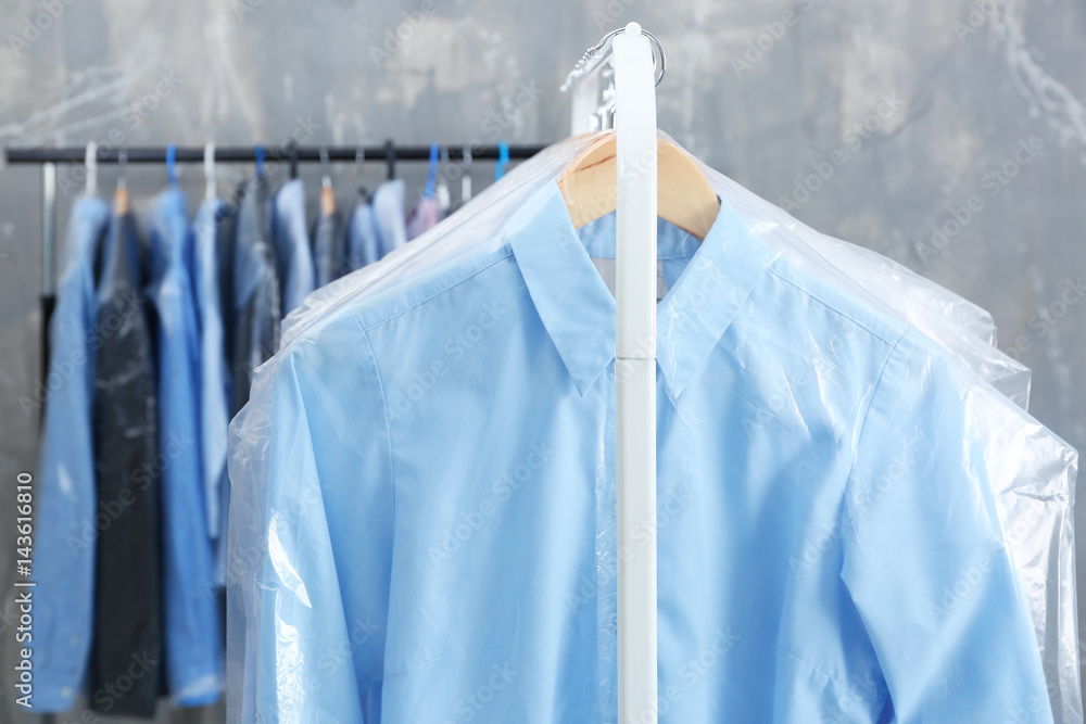 Rack of clean clothes hanging on hangers at dry-cleaning