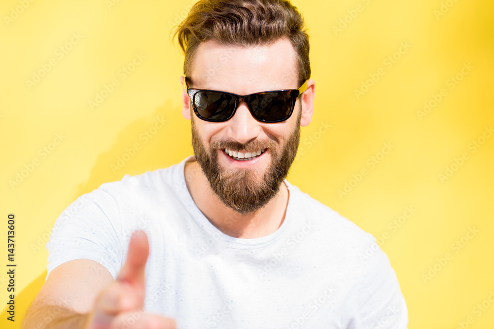 Colorful portrait of a handsome man dressed in white t-shirt on the yellow background