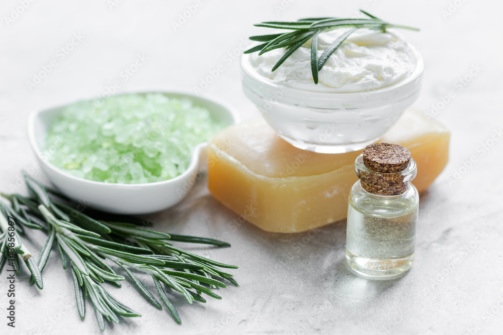 homemade cosmetics with rosemary herbs on white stone background