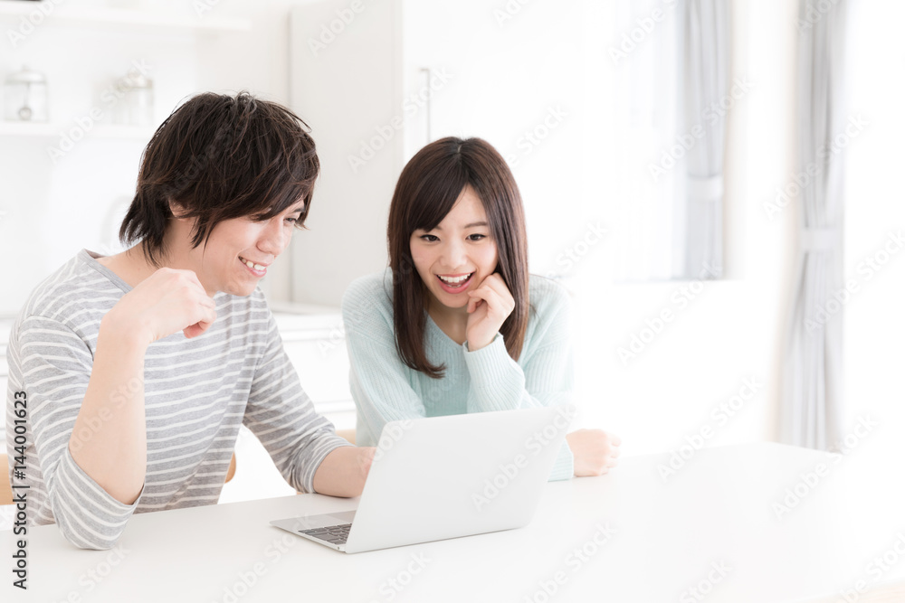 young asian couple using laptop in kitchen