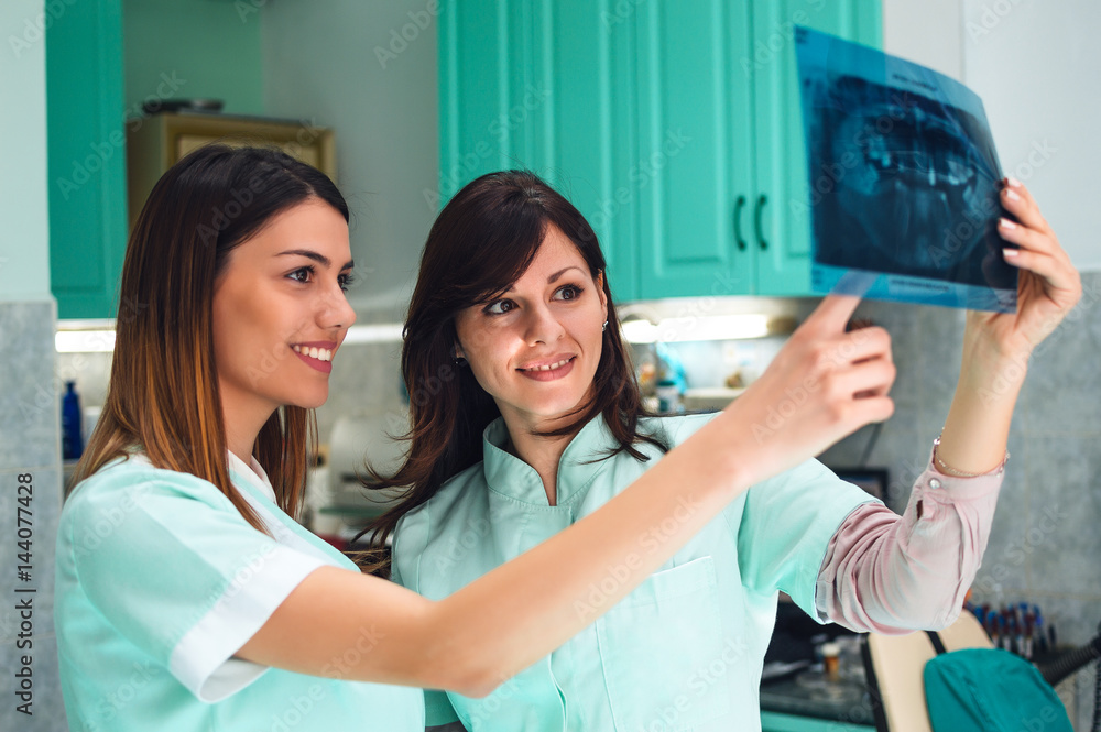 Healthcare, medical and radiology concept - two female dentists looking at x-ray