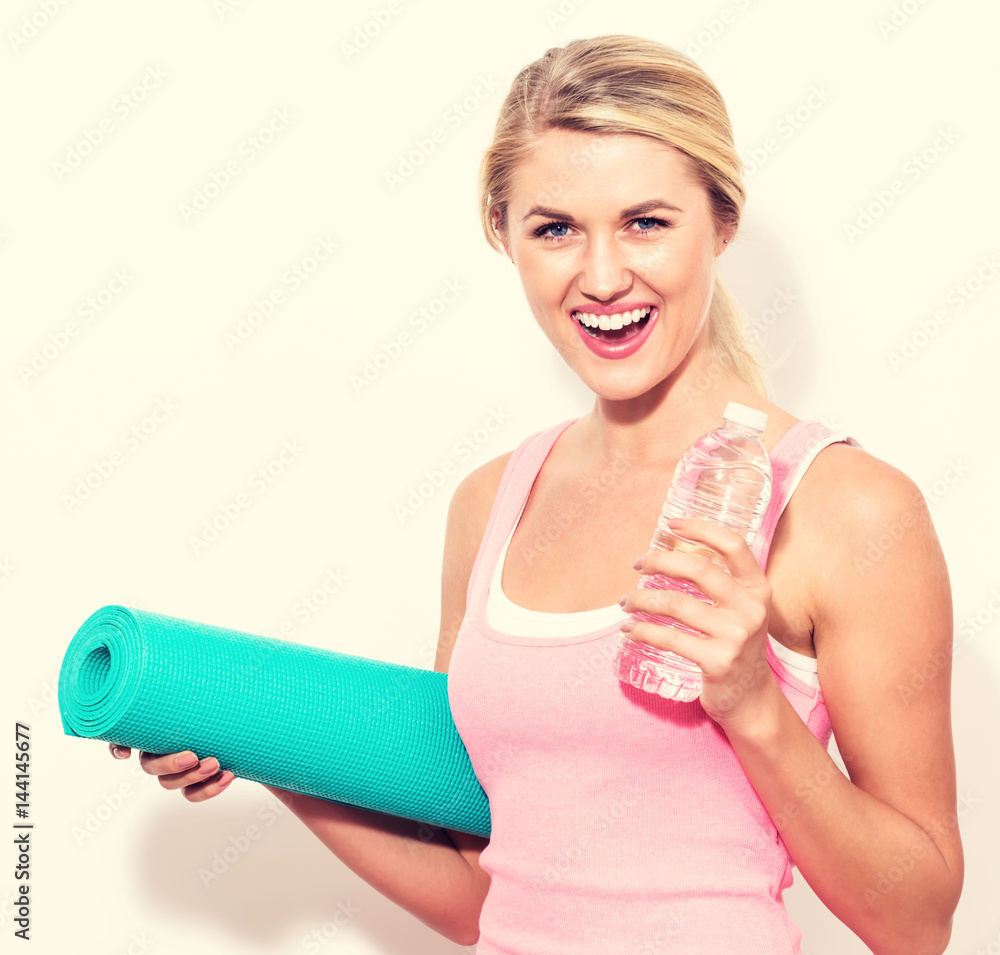 Woman holding yoga mat and water bottle