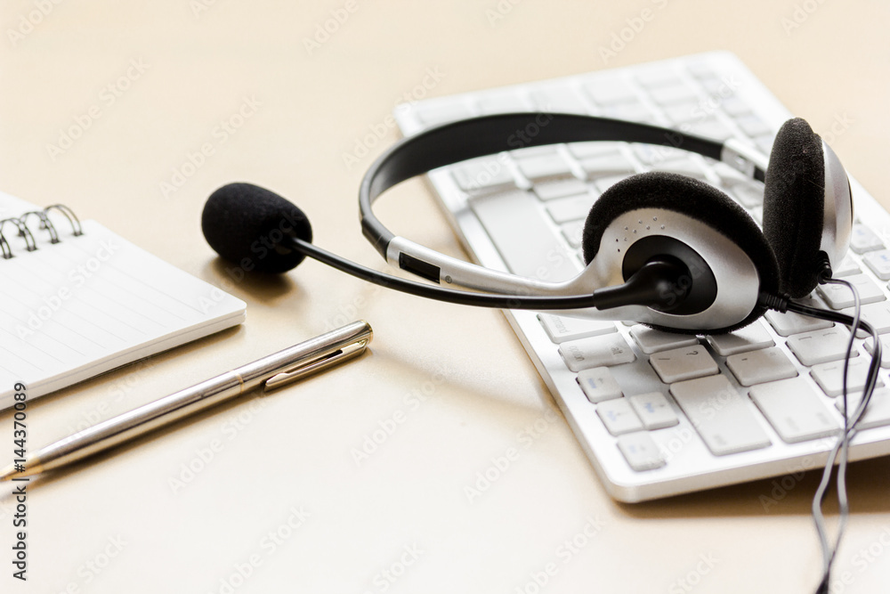 Office desk with headset and keyboard brown background