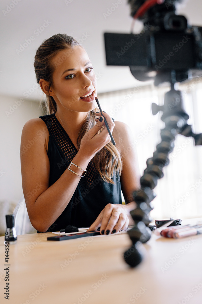 Young female vlogger recording a make-up video for her vlog.