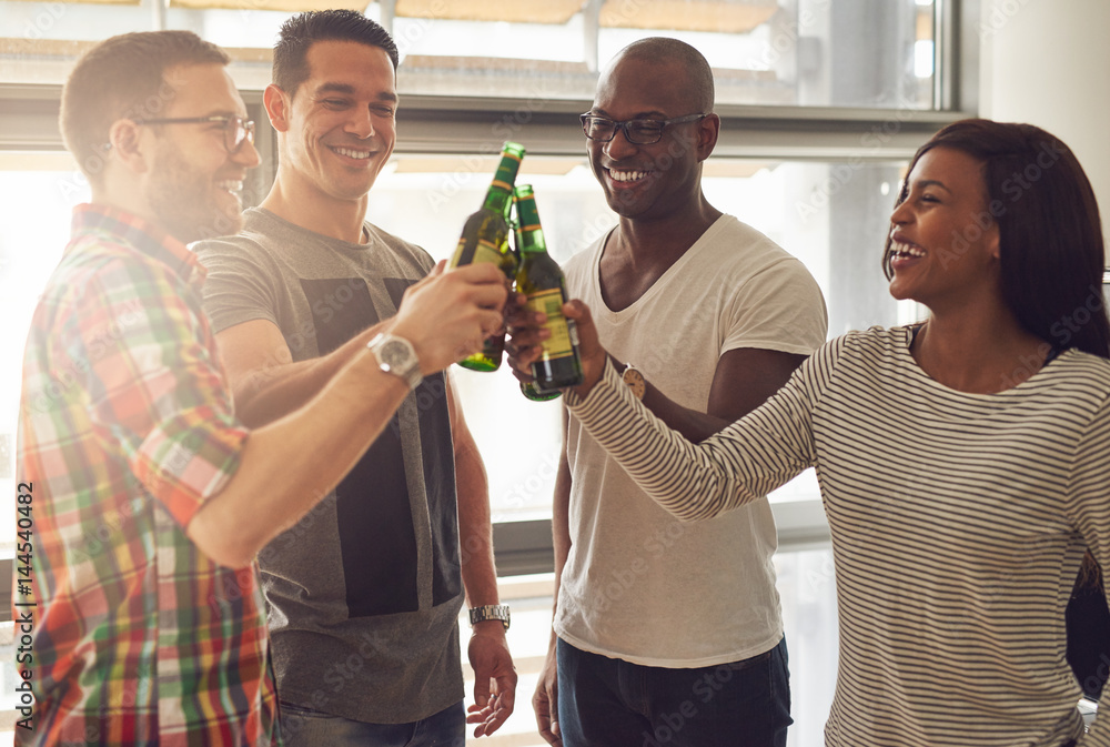 Cheerful people clanging beer bottles in office