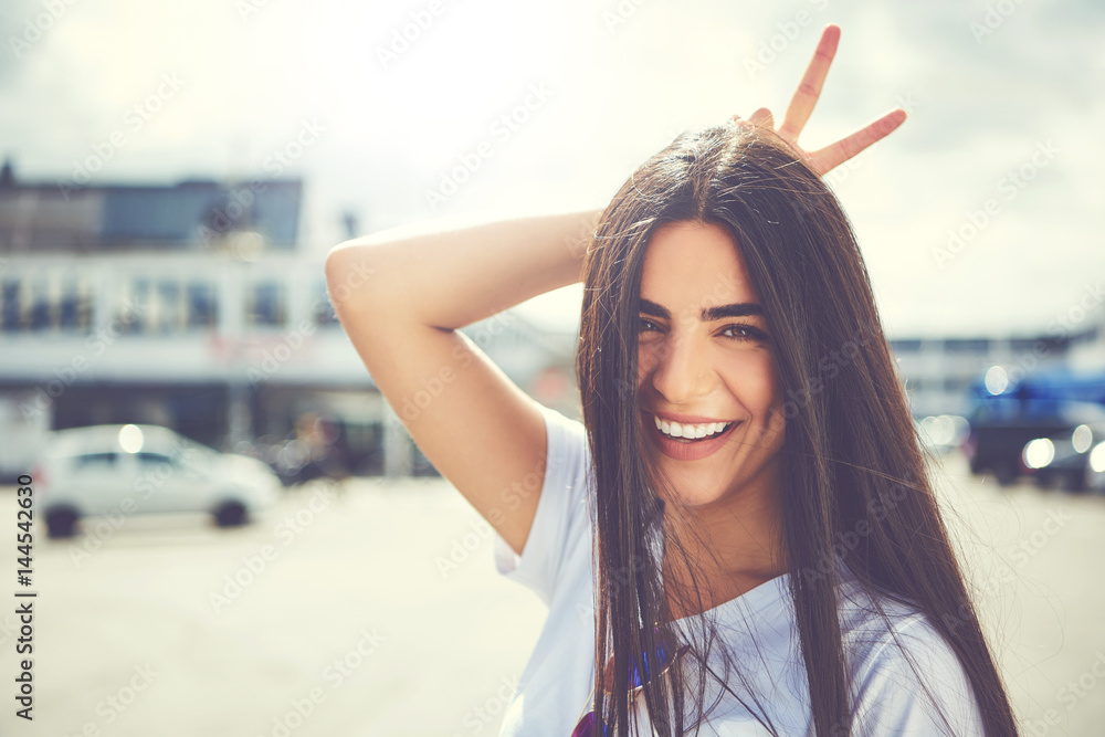 Fun young woman making a horns gesture