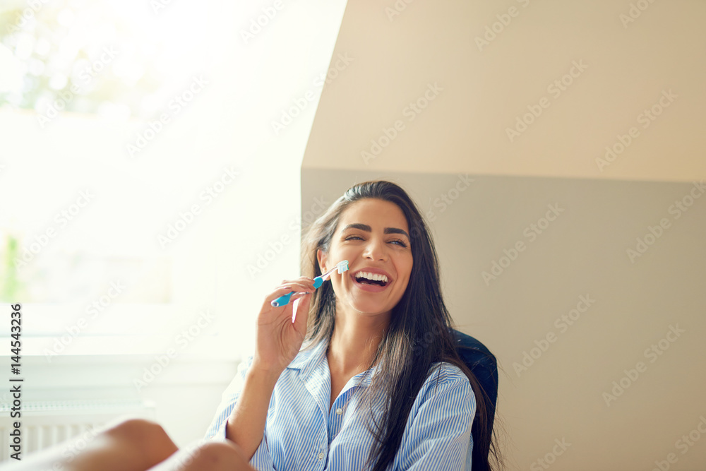 Laughing woman holding toothbrush at home