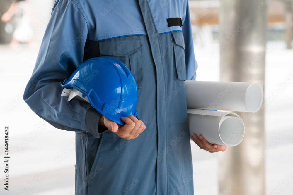 Engineer holding hard hat and blueprint