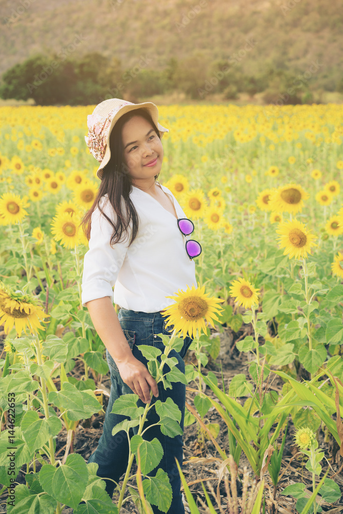 Happy woman in sunflower field smiling with happiness