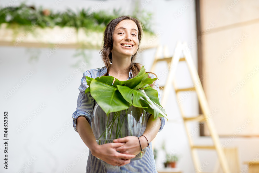 年轻女子在家里种植绿色植物，房间里有大植物