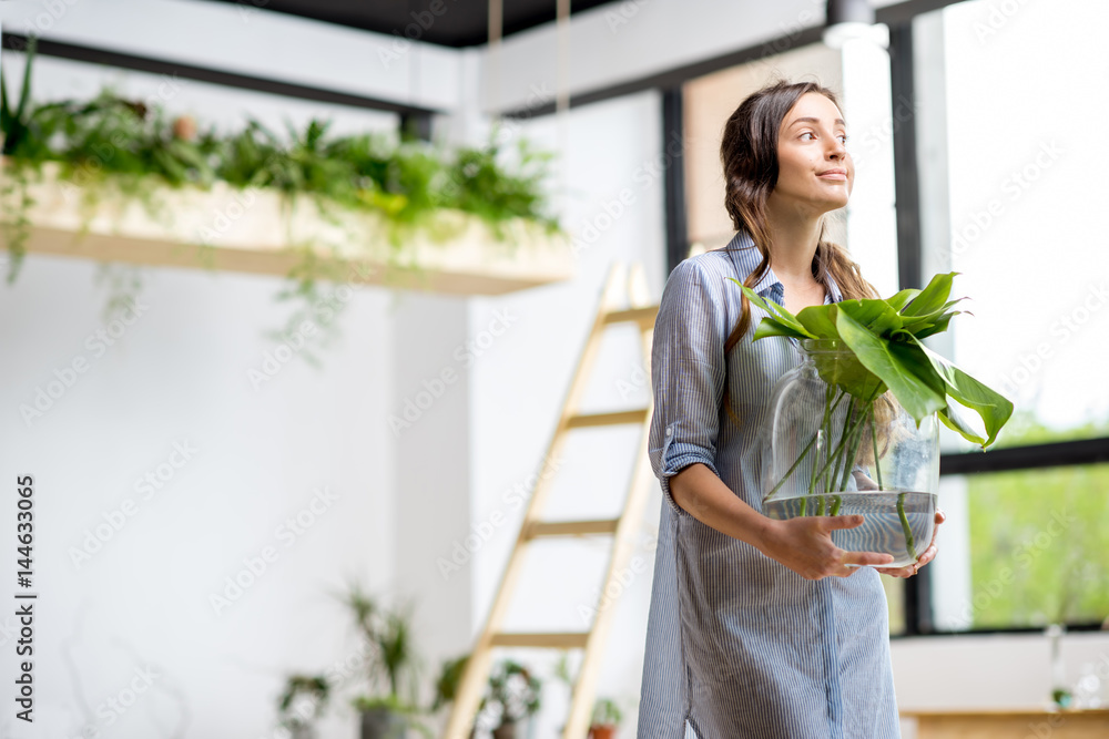 年轻女子在家里种植绿色植物，房间里有大植物