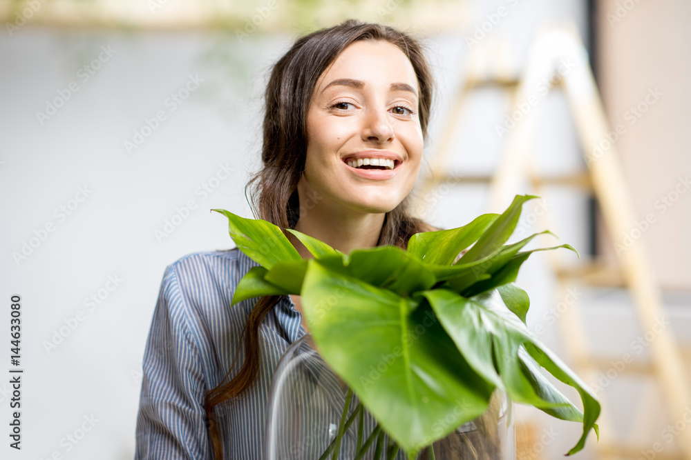 年轻女子在家里种植绿色植物，房间里有大植物