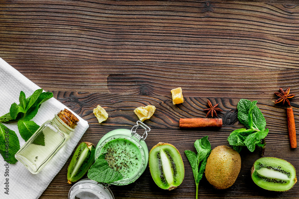 woman cosmetics set with scrub and kiwi table background top view mockup