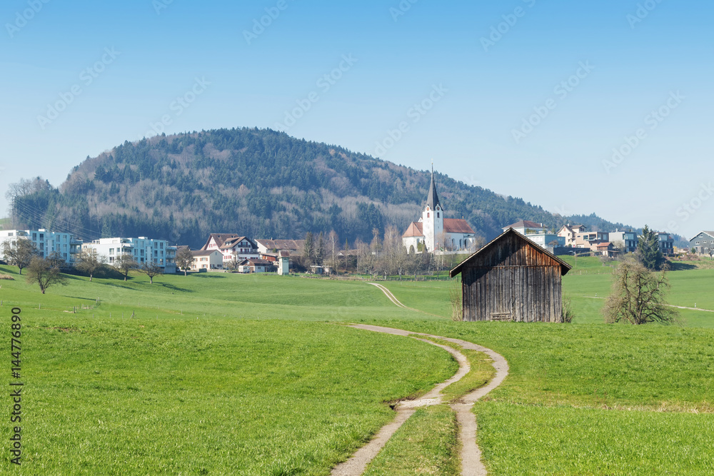 Country landscape, dirt road in front of swiss village