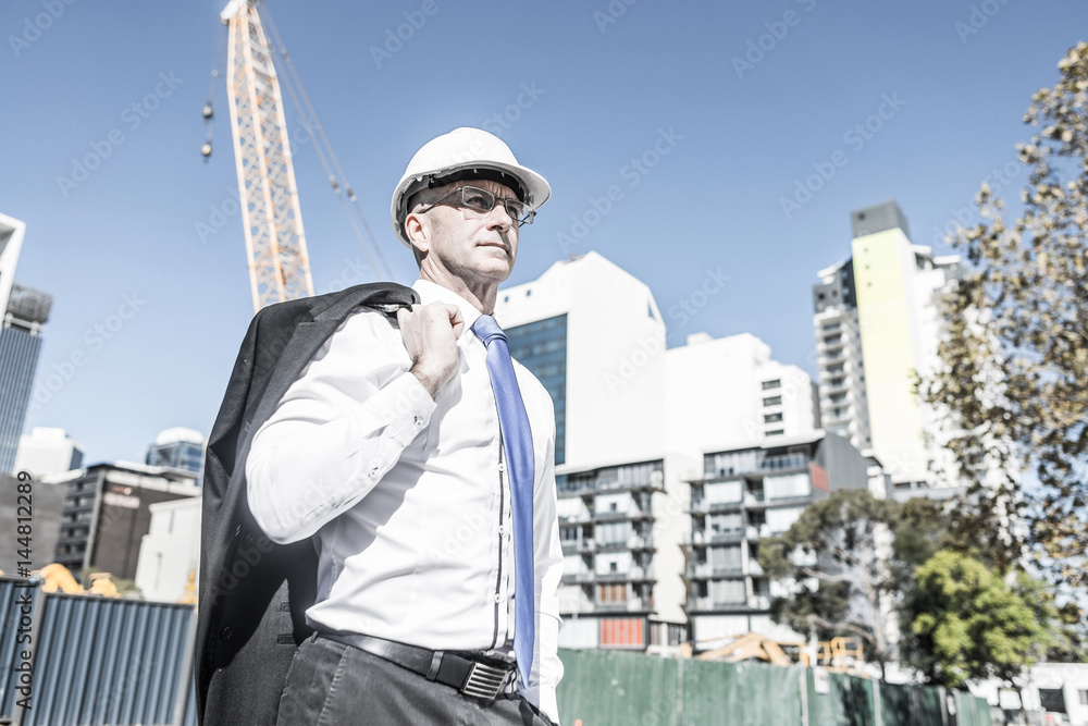 Senior elegant builder man in suit at construction site on sunny