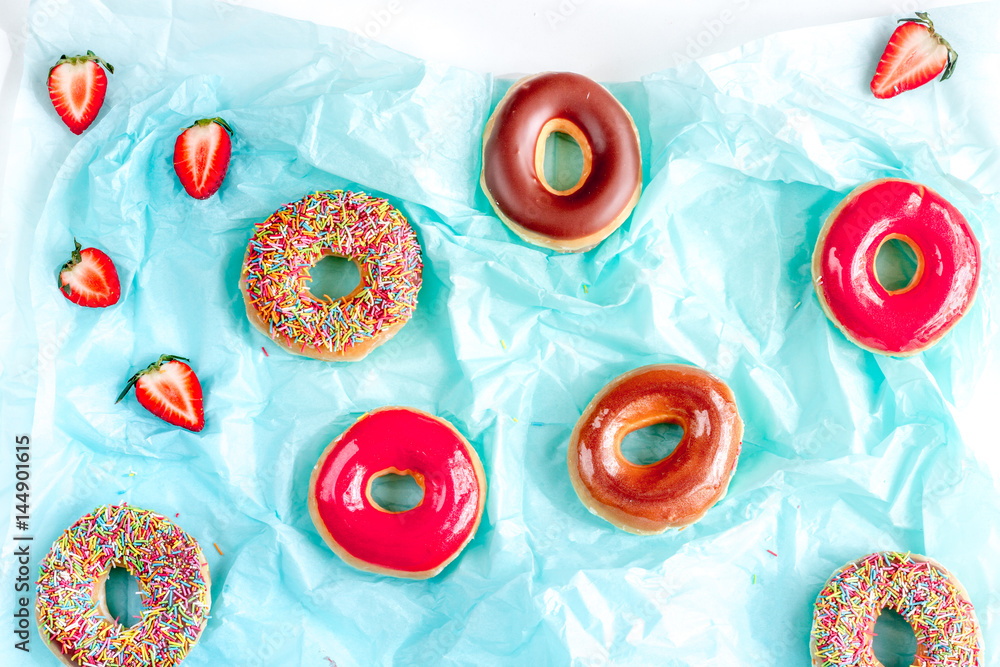 sweet colorful donuts with topping on blue paper background top view pattern