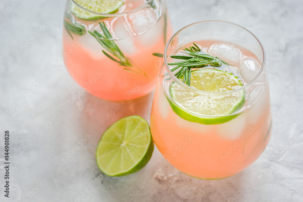 glass of fresh juice with lime and rosemary on stone table background