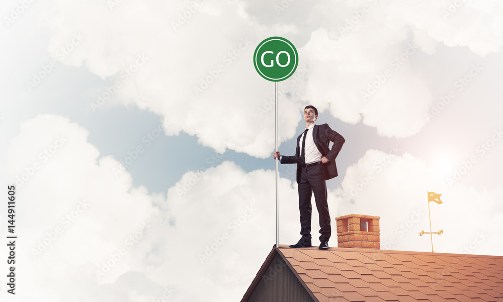 Businessman in suit on house top with ecology concept signboard.