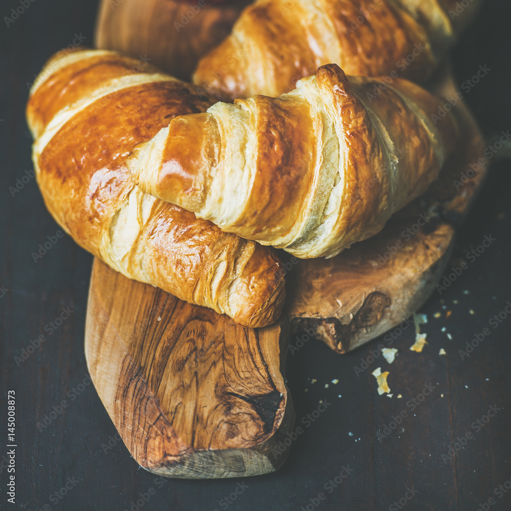 Breakfast concept. Freshly baked croissants with raspberry jam in jar on rustic wooden board over da