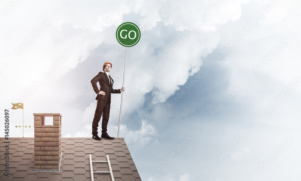 Businessman in suit on house top with ecology concept signboard.