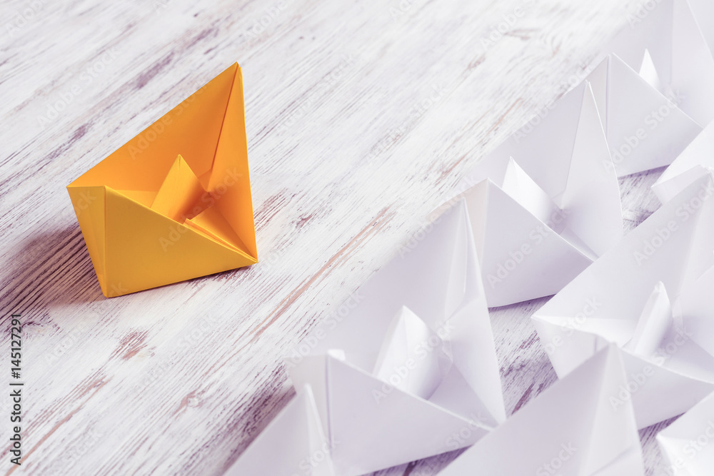 Business leadership concept with white and color paper boats on 