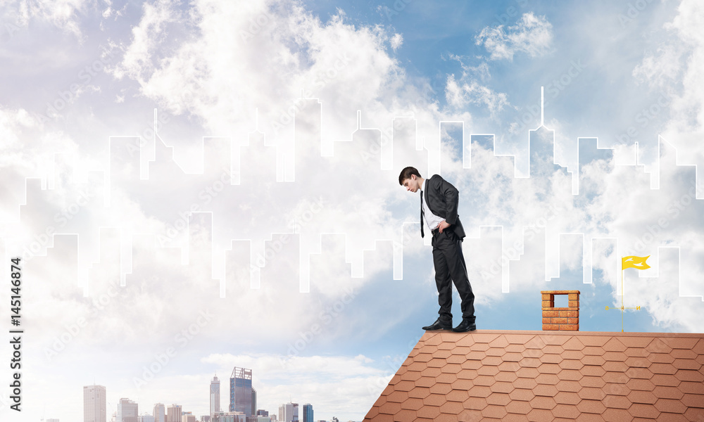 Businessman looking down from roof and modern cityscape at background. Mixed media