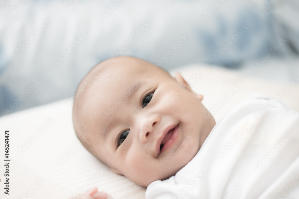 Portrait of cute 3 months Asian baby boy lying down on a blanket and smile.