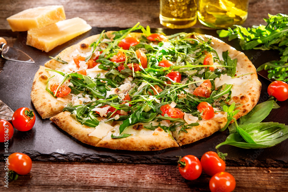 Pizza Caprese with arugula, cheese, yoghurt and cherry tomatoes closeup