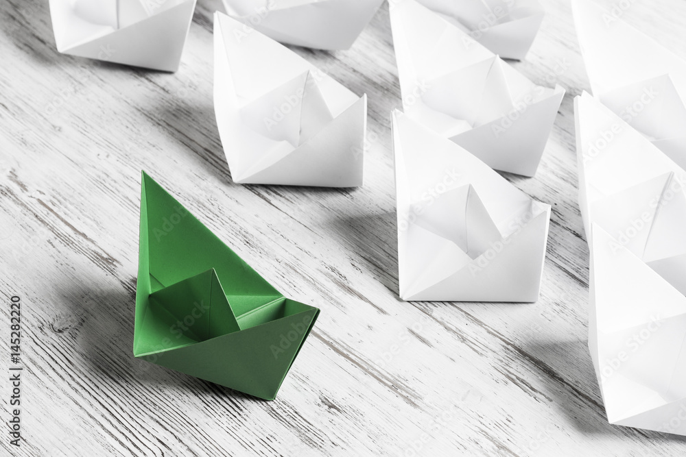 Business leadership concept with white and color paper boats on 