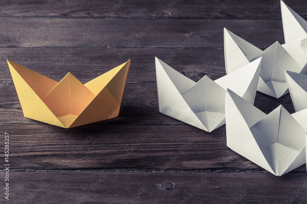 Business leadership concept with white and color paper boats on 