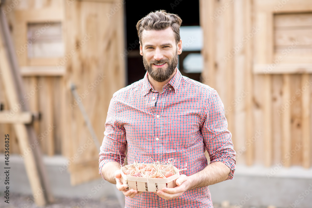 Farmer holding eggs in the wooden pack on the henhouse background