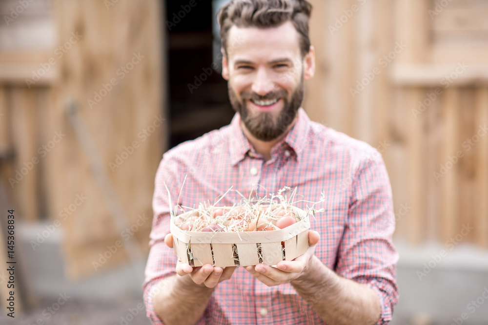 Farmer holding eggs in the wooden pack on the henhouse background. Image focused on the eggs