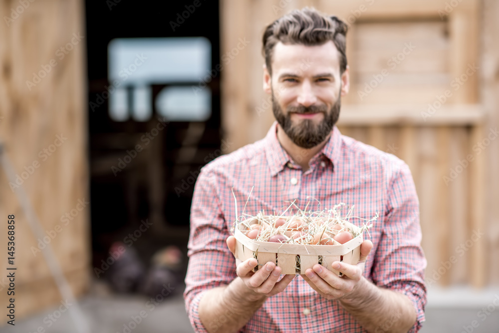 Farmer holding eggs in the wooden pack on the henhouse background. Image focused on the eggs