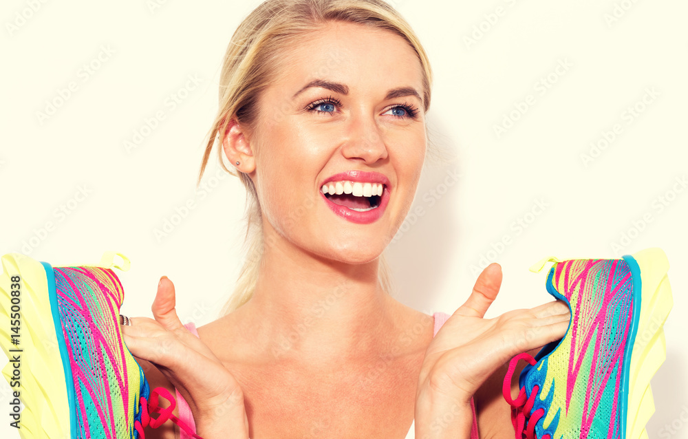 Happy young woman holding shoes