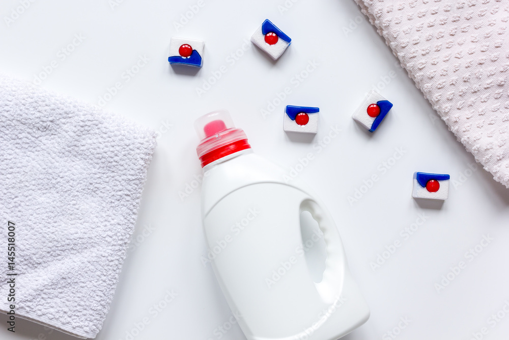 Bath towels stack with detergent bottle in laundry light background top view