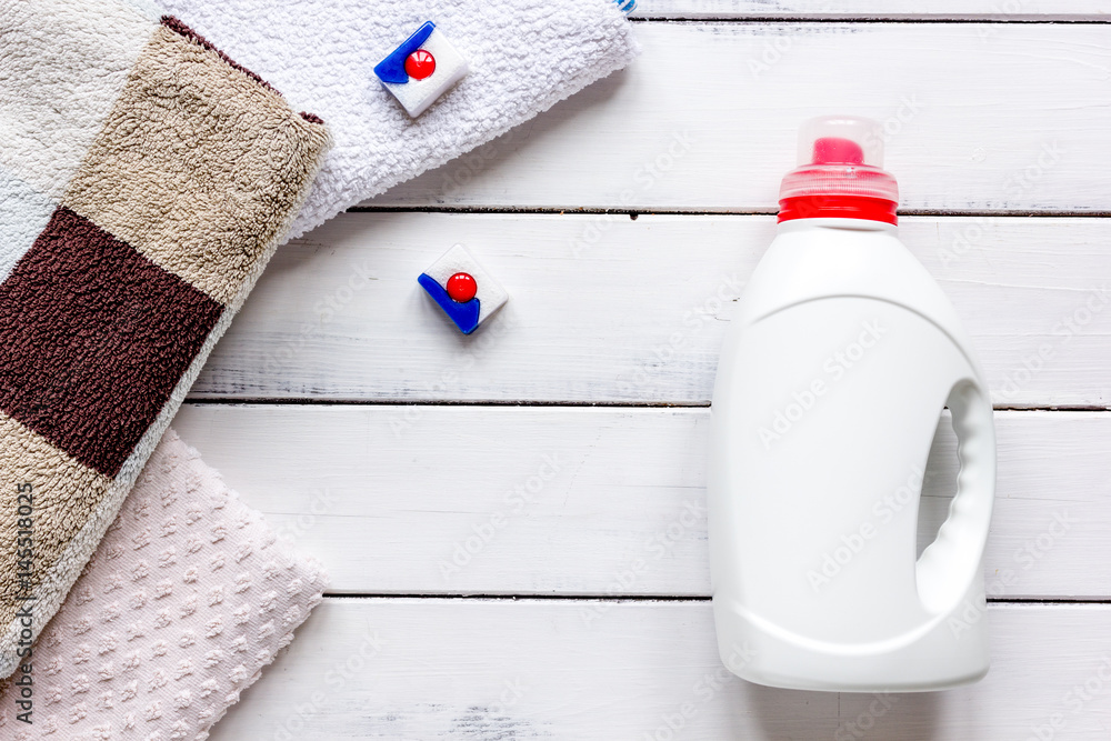 Bath towels stack with detergent bottle in laundry light background top view