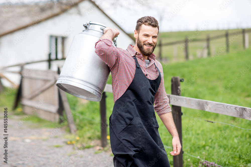 Portrait of a handsome milkman in apron walking with milk container outdoors on the rural scene back