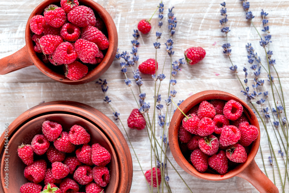 raspberry in pottery and lavender flowers on rustic background top view